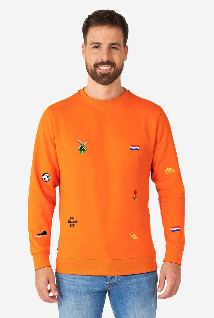 Mann trägt einen orangefarbenen Pullover mit niederländischen Ikonen