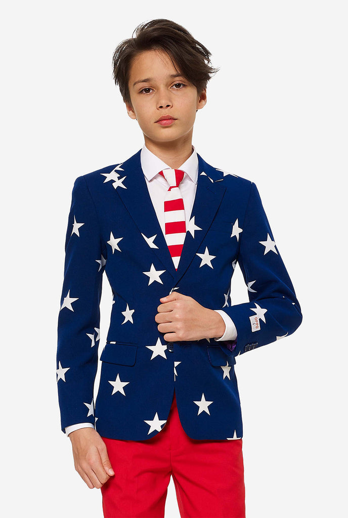 Teenager, der einen formellen Anzug am 4. Juli mit dem offiziellen USA farben trägt, bestehend aus blauer Jacke und roten Hosen.