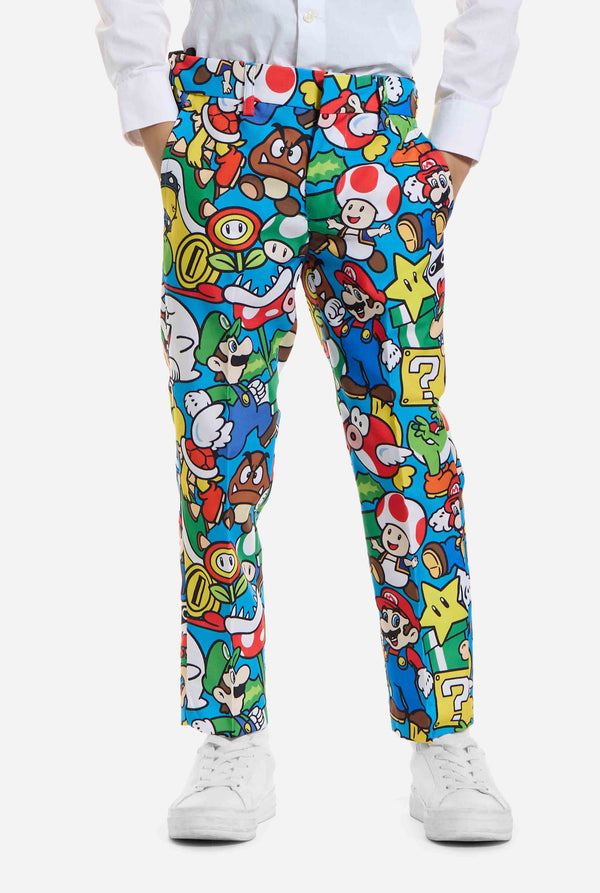Bild eines Kindes, das einen Anzug mit Super Mario-Allover-Print trägt, bestehend aus Blazer, Hose und Krawatte. Die Hauptfarbe ist blau, aber es gibt auch gelb, rot und weiß.