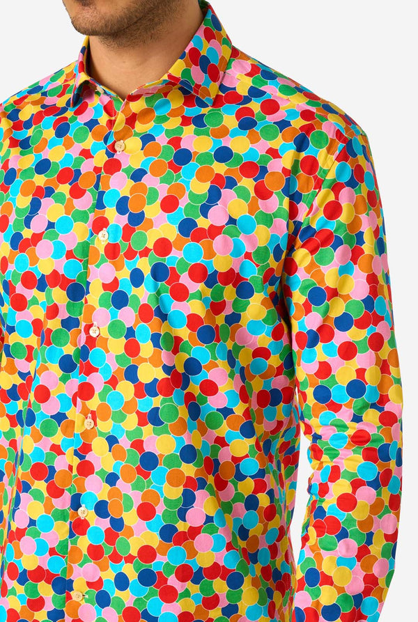 Person, die ein buntes, gepunktetes Konfetti-Shirt mit einfarbigem Hintergrund trägt, Nahaufnahme.