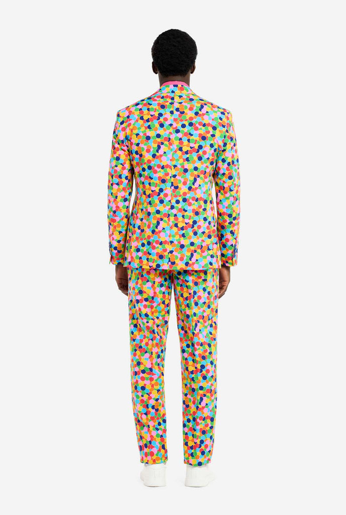 Bild eines Mannes, der einen OppoSuits Confetteroni-Herrenanzug mit Konfetti-Aufdruck und rosa Herrenhemd trägt. Der Anzug besteht aus Hose, Jacke und Krawatte.