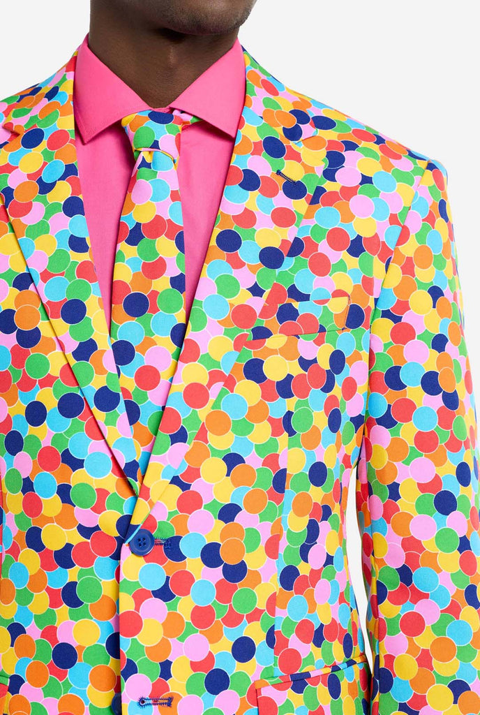 Bild eines Mannes, der einen OppoSuits Confetteroni-Herrenanzug mit Konfetti-Aufdruck und rosa Herrenhemd trägt. Der Anzug besteht aus Hose, Jacke und Krawatte.