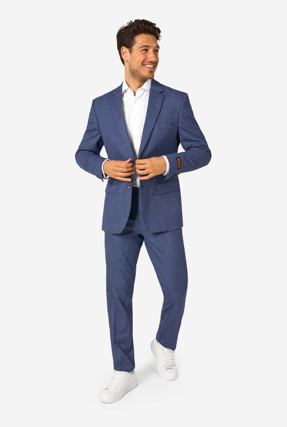 Ein Mann, der einen dunkelblau-blau karierten Anzug mit einem weißen Hemd trägt. Der Anzug hat eine moderne Passform mit zwei Knöpfen und Pattentaschen. Er steht vor einem schlichten weißen Hintergrund.