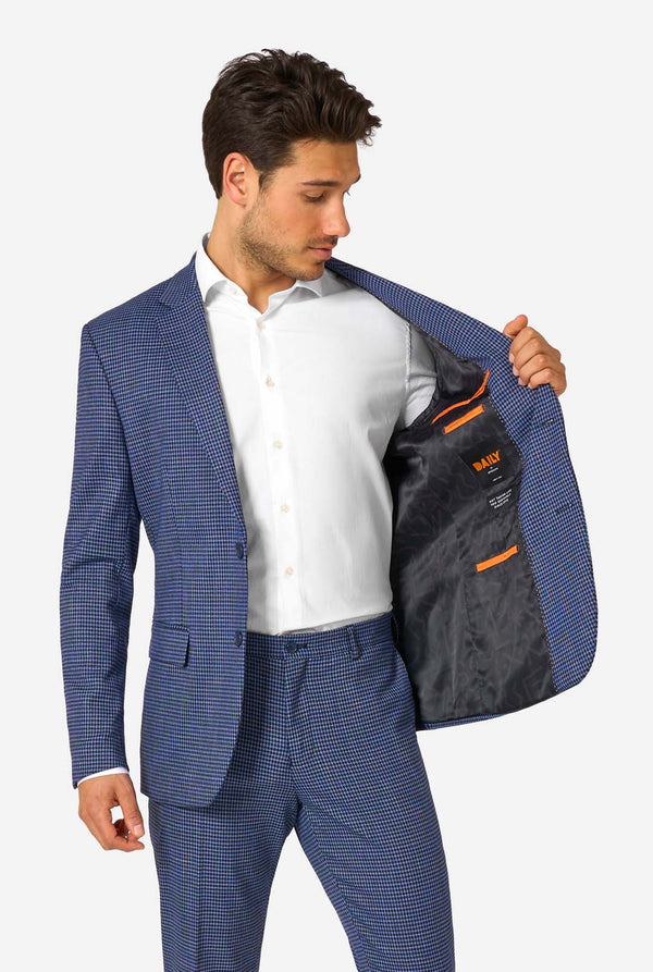 Ein Mann, der einen dunkelblau-blau karierten Anzug mit einem weißen Hemd trägt. Der Anzug hat eine moderne Passform mit zwei Knöpfen und Pattentaschen. Er steht vor einem schlichten weißen Hintergrund. Hält seine Jacke offen