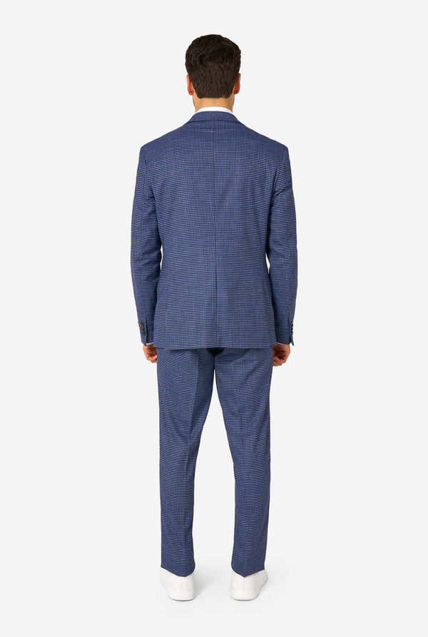 Ein Mann, der einen dunkelblau-blau karierten Anzug mit einem weißen Hemd trägt. Der Anzug hat eine moderne Passform mit zwei Knöpfen und Pattentaschen. Er steht vor einem schlichten weißen Hintergrund. Ansicht von hinten