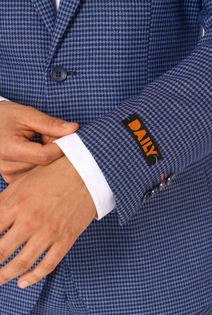 Ein Mann, der einen dunkelblau-blau karierten Anzug mit einem weißen Hemd trägt. Der Anzug hat eine moderne Passform mit zwei Knöpfen und Pattentaschen. Er steht vor einem schlichten weißen Hintergrund. Nahaufnahme der Ärmel