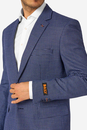 Ein Mann, der einen dunkelblau-blau karierten Anzug mit einem weißen Hemd trägt. Der Anzug hat eine moderne Passform mit zwei Knöpfen und Pattentaschen. Er steht vor einem schlichten weißen Hintergrund. Nahaufnahme der Brust