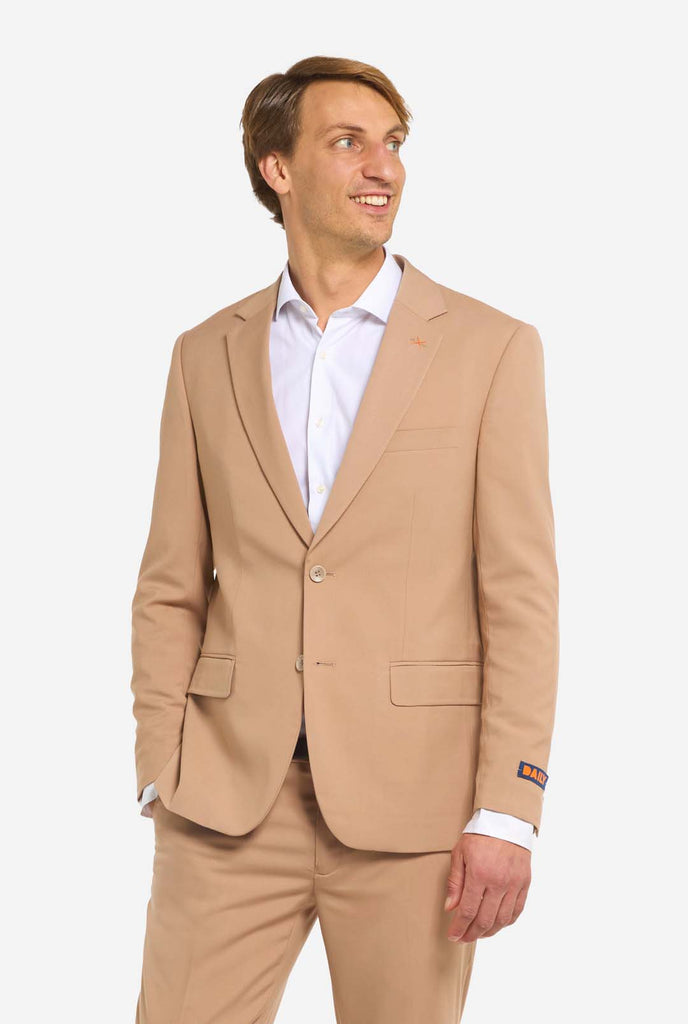 Bild mit hellgrauem Hintergrund und Mann trägt Dark Sand Herrenanzug und weißes Hemd. Anzüge besteht aus Blazer und Hose. Mann schaut zur Seite.