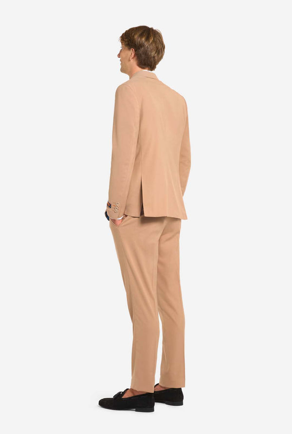 Bild mit hellgrauem Hintergrund und Mann trägt Dark Sand Herrenanzug und weißes Hemd. Der Anzug besteht aus Blazer und Hose. Ansicht von hinten.