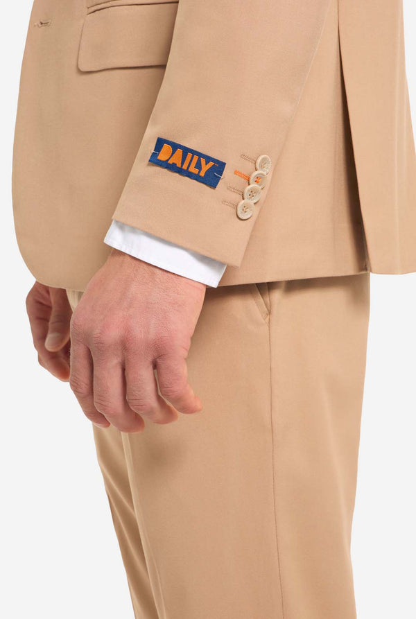 Bild mit hellgrauem Hintergrund und Mann trägt Dark Sand Herrenanzug und weißes Hemd. Der Anzug besteht aus Blazer und Hose. Ansicht von der Seite.