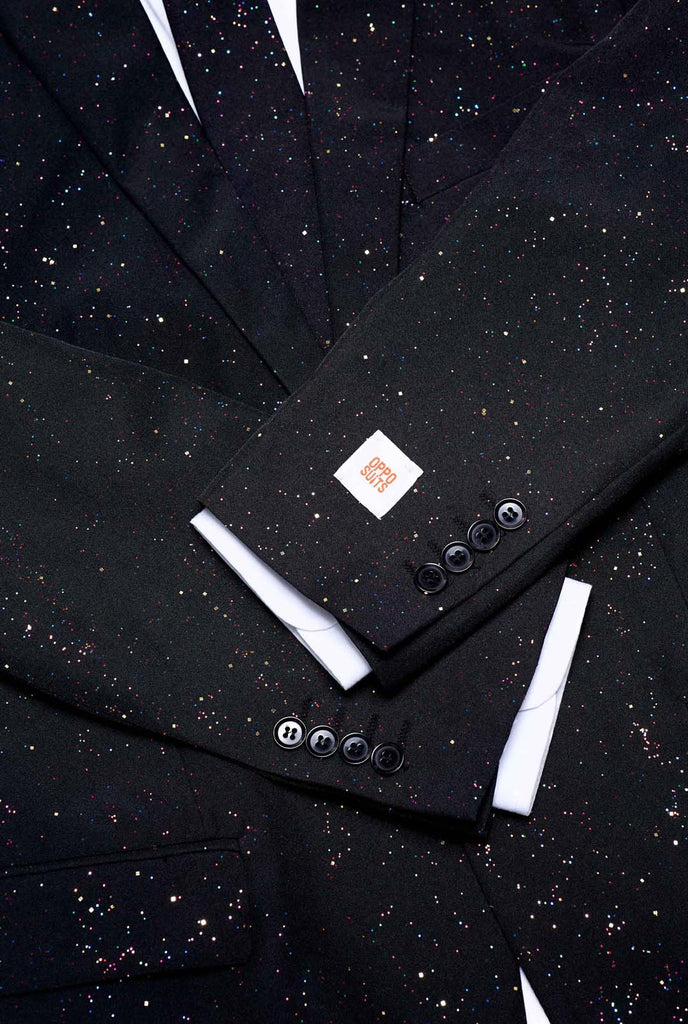 Bild einen OppoSuits Glitzy Glitter-Herrenanzug mit Glitzer und weißem Herrenhemd trägt. Der Anzug besteht aus Hose, Jackett und Krawatte.