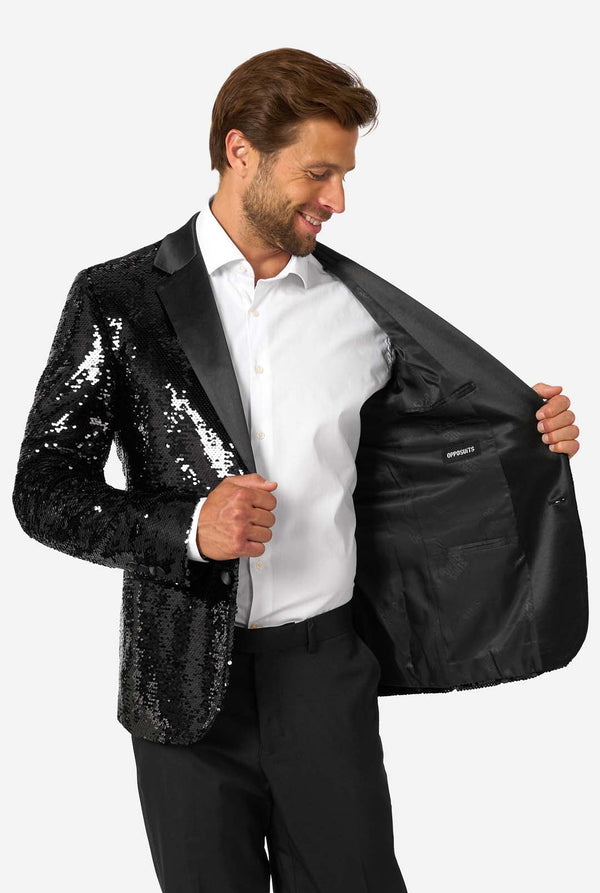 Ein Mann trägt einen schwarzen, mit Pailletten besetzten Blazer mit Schalkragen aus Satin.