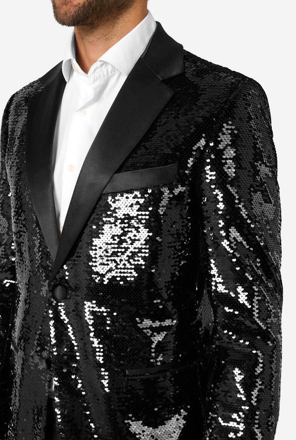 Ein Mann trägt einen schwarzen, mit Pailletten besetzten Blazer mit Schalkragen aus Satin.