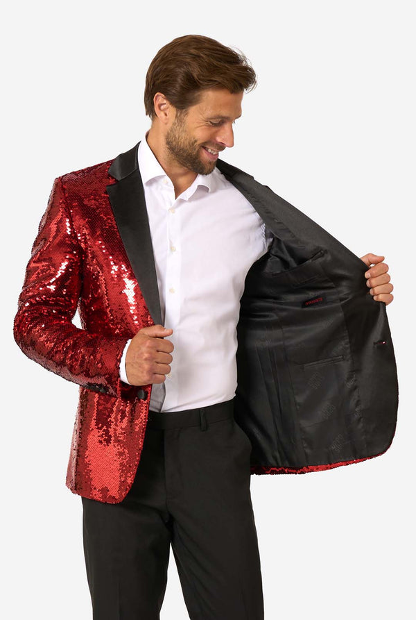 Ein Mann trägt einen glänzenden, roten Blazer mit Pailletten und schwarzen Kragen.