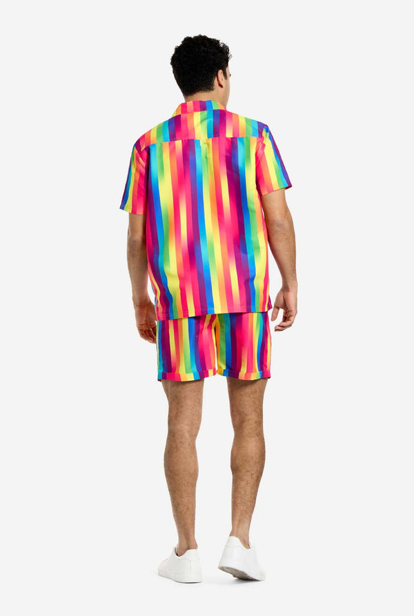 Ein Mann trägt ein vertikal gestreiftes Sommerset in Regenbogenfarben, bestehend aus Hemd und Shorts. Er ist von der Kamera abgewandt und zeigt die Rückseite des Sommersets.