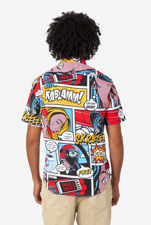 Person, die ein farbenfrohes T-Shirt mit Comic-Thema und verschiedenen Grafiken und Texten trägt.