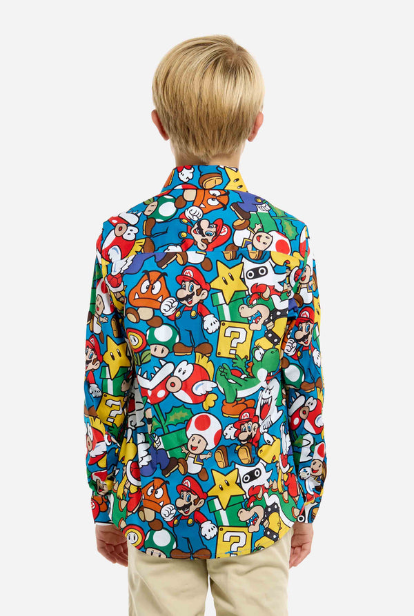 Bild eines Teenagers, der ein T-Shirt mit Super Mario-Allover-Print trägt. Die Hauptfarbe ist Blau, aber es gibt auch Gelb, Rot und Weiß.