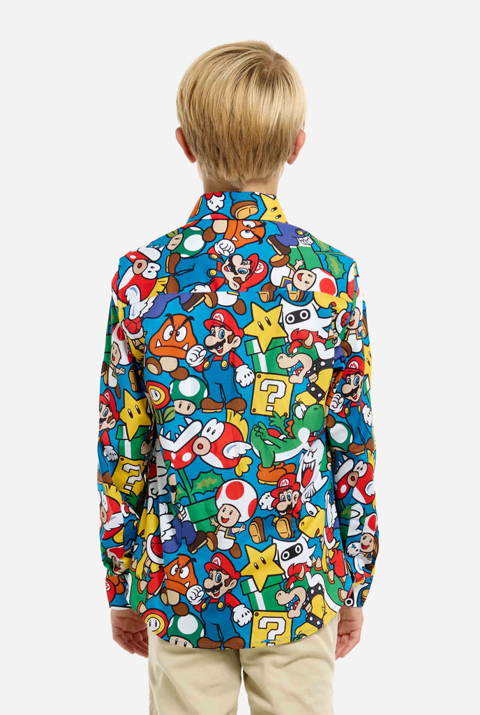 Bild eines Teenagers, der ein T-Shirt mit Super Mario-Allover-Print trägt. Die Hauptfarbe ist Blau, aber es gibt auch Gelb, Rot und Weiß.