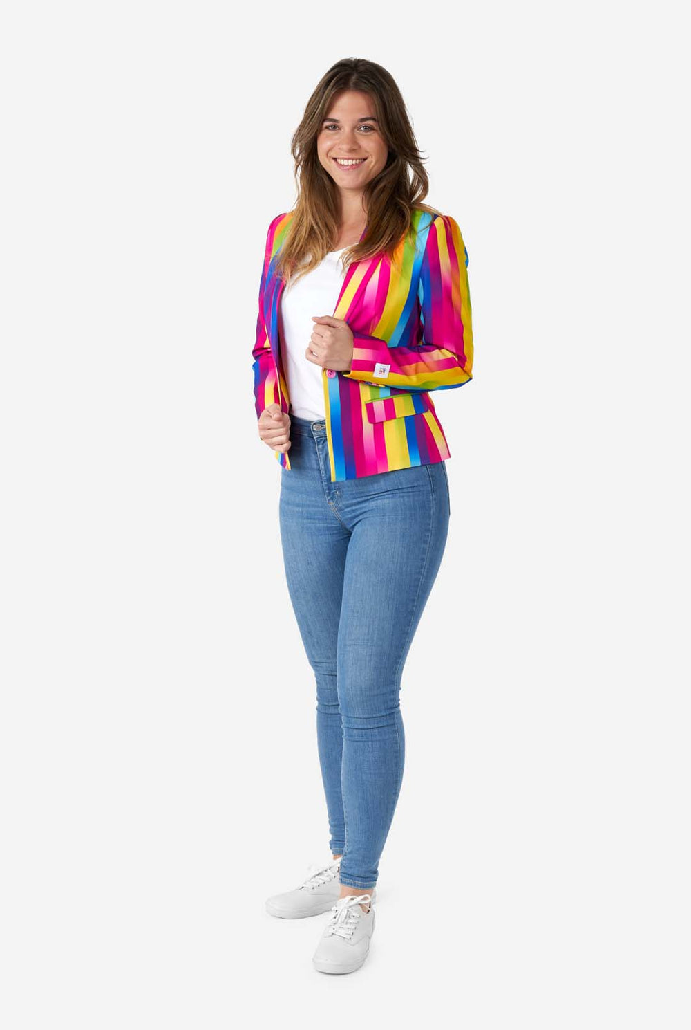 Bild einer Frau, die einen vertikal gestreiften Damenblazer in Regenbogenfarben, ein weißes Hemd und blaue Jeans trägt. Sie hält die Seiten des Blazers.
