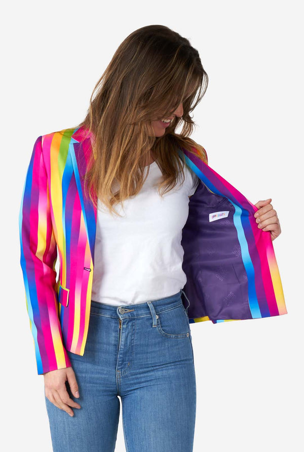 Bild einer Frau in einem vertikal gestreiften, regenbogenfarbenen Damenblazer, einem weißen Hemd und blauen Jeans. Sie hält eine Seite des Blazers offen und zeigt das violette Futter.