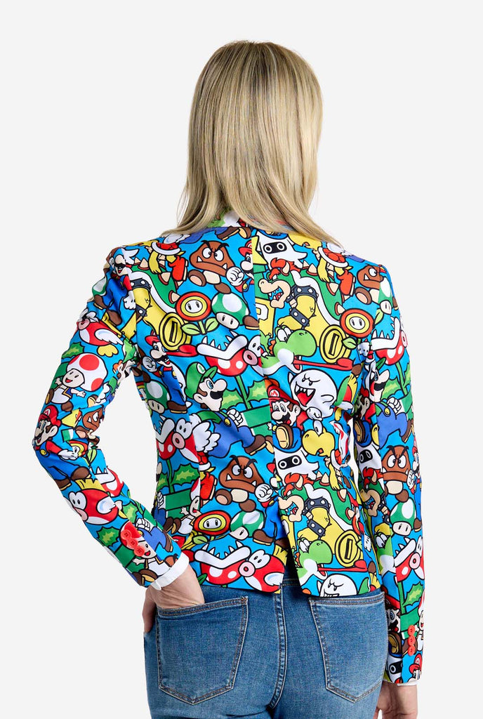 Frau trägt einen Super Mario-Blazer mit Allover-Print und ikonischen Super Mario-Figuren. Die Basis ist hellblau, aber es gibt auch Gelb, Rot und Weiß.