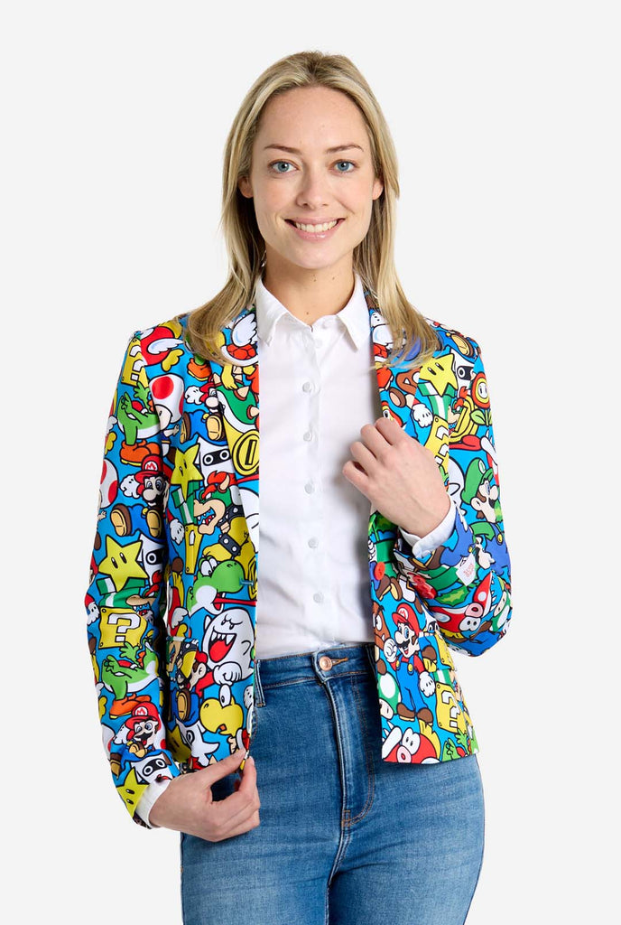 Frau trägt einen Super Mario-Blazer mit Allover-Print und ikonischen Super Mario-Figuren. Die Basis ist hellblau, aber es gibt auch Gelb, Rot und Weiß.