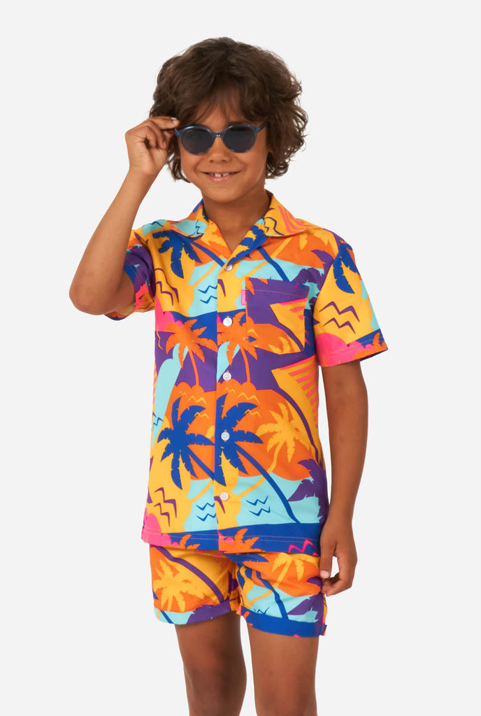 Jongen draagt kleurrijke palm zomerset, bestaande uit korte broek en shirt