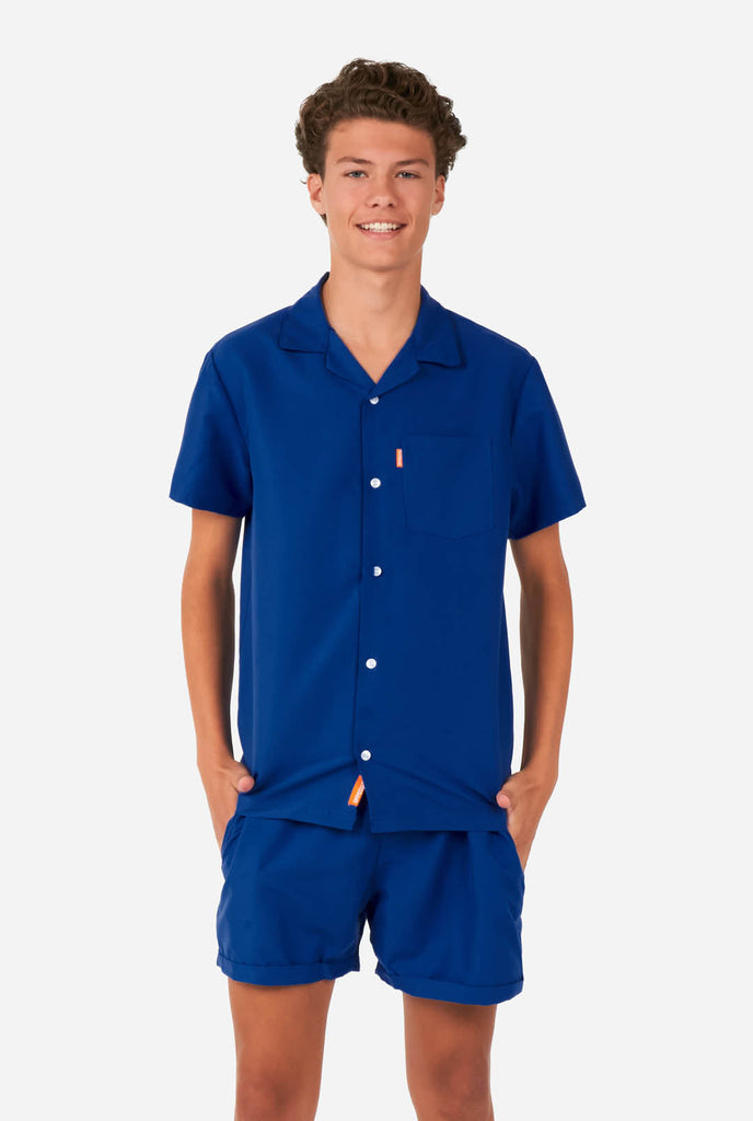 Tiener draagt blauwe zomerset, bestaande uit shirt en short.