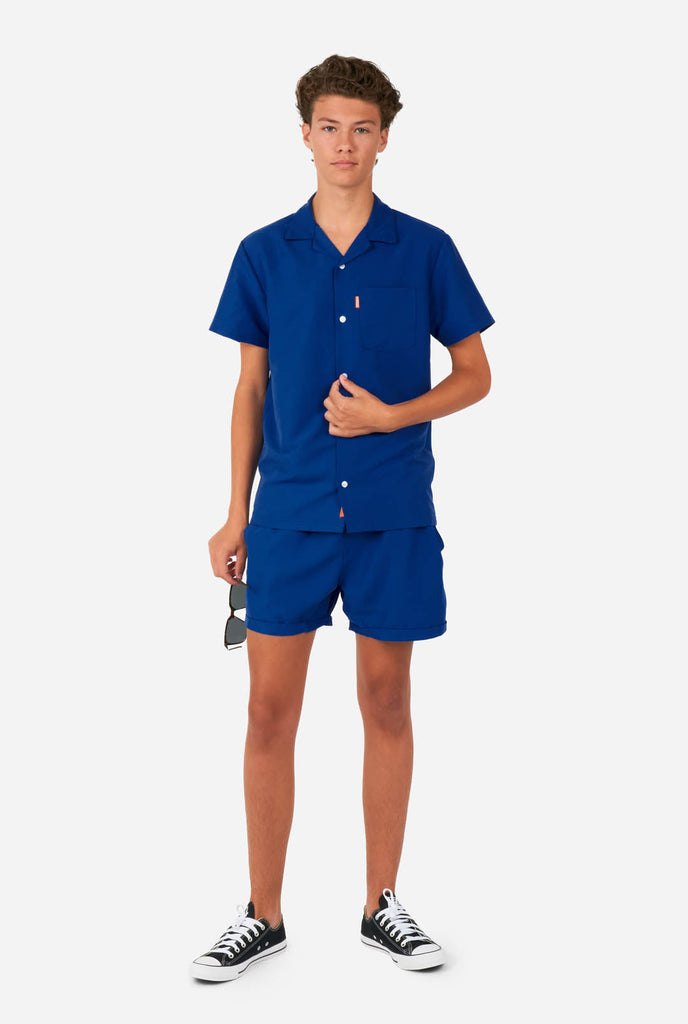 Tiener draagt blauwe zomerset, bestaande uit shirt en short.