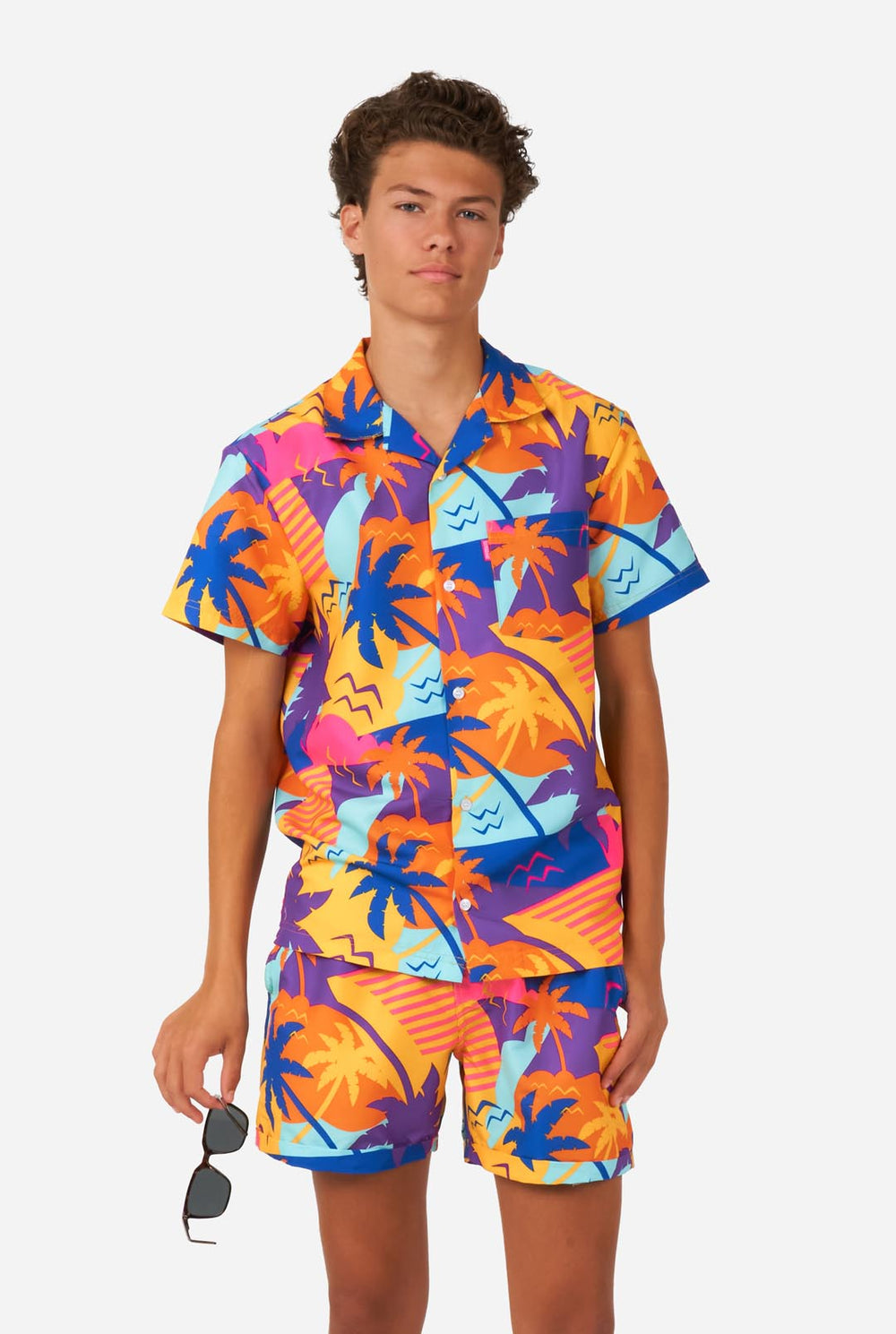Teenager trägt buntes Palmen-Sommerset, bestehend aus Shirt und Shorts.