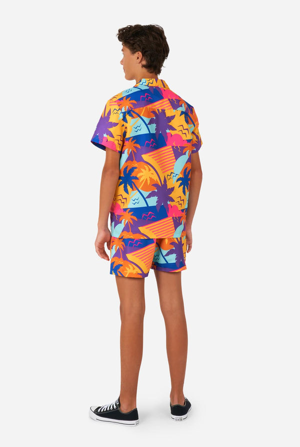 Teenager trägt buntes Palmen-Sommerset, bestehend aus Shirt und Shorts.