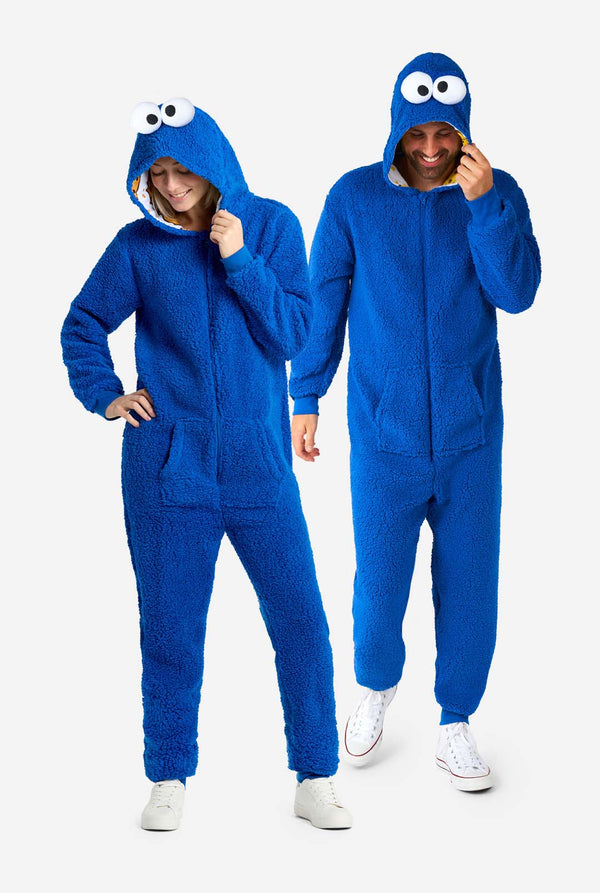 Mann und Frau tragen einen blauen Plüsch-Einteiler mit dem Krümelmonster für Erwachsene. Sie stehen nebeneinander und halten die Kapuze mit der Hand.