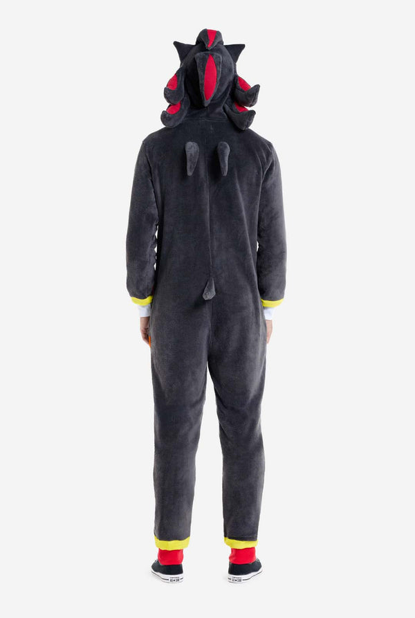 Ein Mann trägt einen plüschigen schwarzen Onesie, inspiriert vom beliebten Igel Shadow. Er besticht durch stachelige rote und schwarze Akzente an der Kapuze, ein weißes Brustemblem und gelbe Handgelenksdetails. Der Onesie aus weichem Fleece bietet Komfort und ein verspieltes Design für Cosplay, zum Entspannen oder für Themenveranstaltungen. Rückansicht. Perfekt für Fans von Gaming- oder Zeichentrickfiguren.