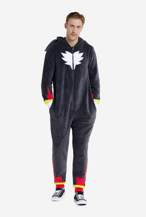 Ein Mann trägt einen plüschigen schwarzen Onesie, inspiriert vom beliebten Igel Shadow. Er besticht durch stachelige rote und schwarze Akzente an der Kapuze, ein weißes Brustemblem und gelbe Handgelenksdetails. Der Onesie aus weichem Fleece bietet Komfort und ein verspieltes Design für Cosplay, Lounge-Abende oder Themenveranstaltungen. Die Person lächelt, während die Kapuze auf ihrem Rücken liegt. Perfekt für Fans von Gaming- oder Zeichentrickfiguren. Ganzkörperbild.