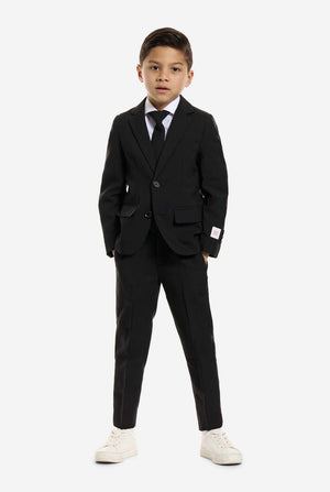 Der Junge trägt einen schwarzen Anzug von OppoSuits.