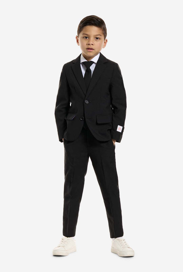 Der Junge trägt einen schwarzen Anzug von OppoSuits.