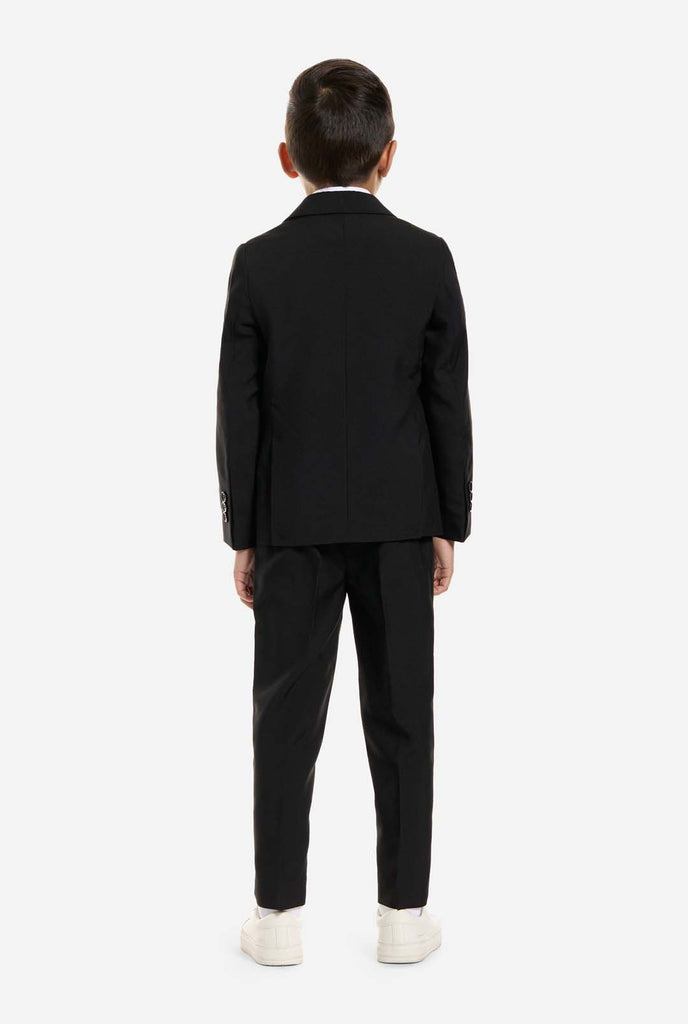 Der Junge trägt einen schwarzen Anzug von OppoSuits.
