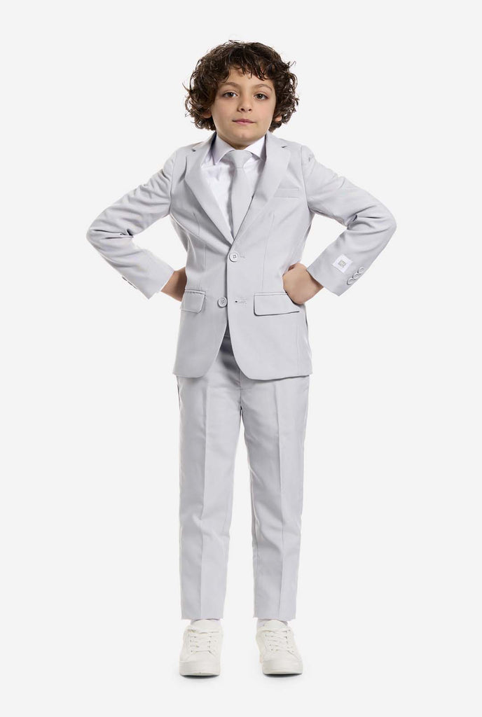 Auf diesem Bild trägt ein Kind einen grauen formellen Jungenanzug mit passender Krawatte und einem weißen Hemd. Der Anzug besteht aus einer Jacke, einer Hose und einer Krawatte zum Anstecken.