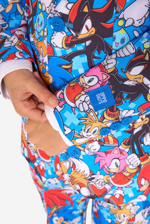 Junge in einem farbenfrohen Sonic-Teenie-Anzug mit bunten Aufdrucken von Sonic the Hedgehog-Figuren wie Sonic, Knuckles, Tails und Amy, gepaart mit einer passenden Krawatte und einem weißen Hemd. Nahaufnahme der Ärmel.