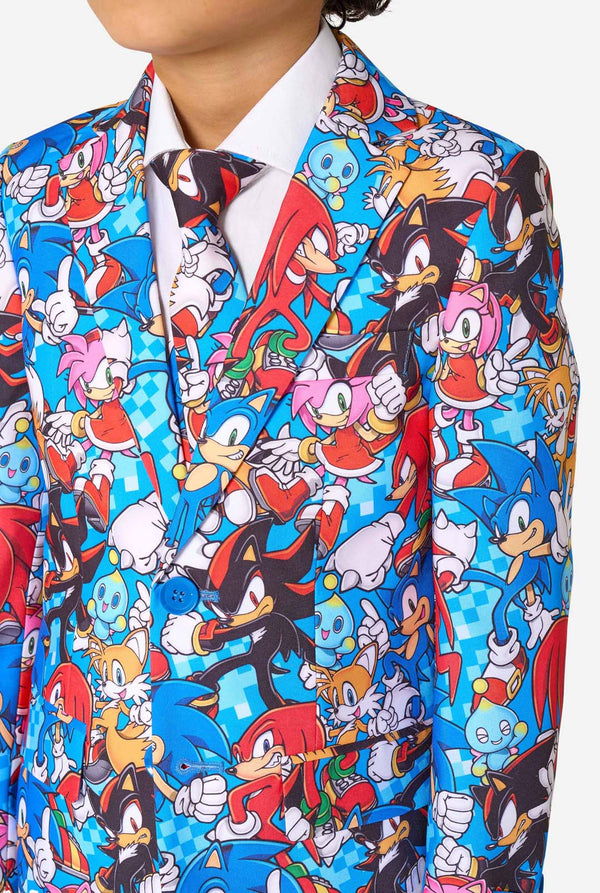 Junge in einem farbenfrohen Sonic-Teenie-Anzug mit bunten Aufdrucken von Sonic the Hedgehog-Figuren wie Sonic, Knuckles, Tails und Amy, gepaart mit einer passenden Krawatte und einem weißen Hemd. Nahaufnahme der Brust.