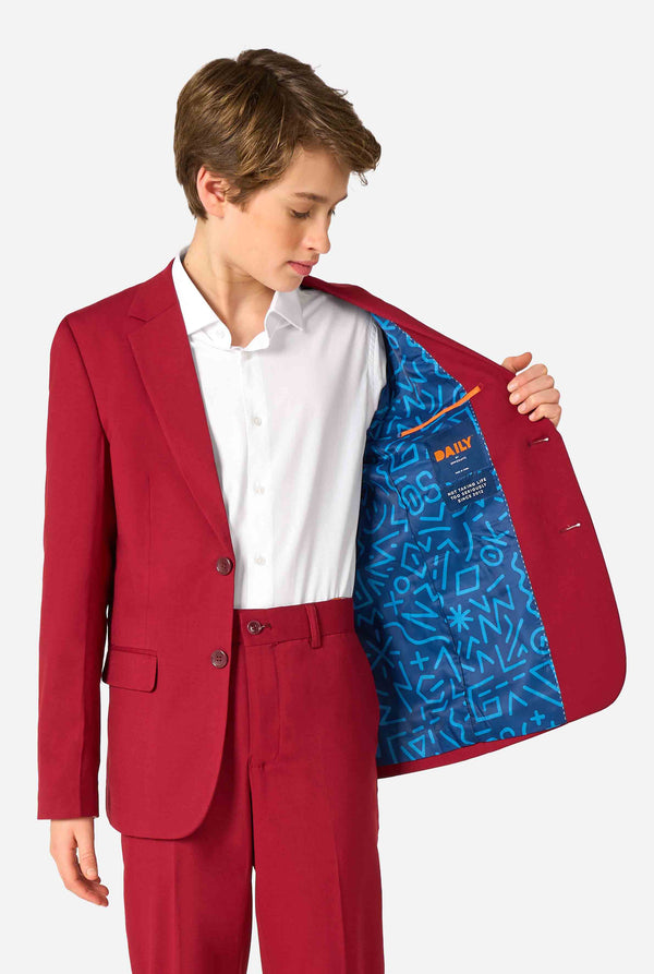 Teenager trägt einen eleganten burgunderroten Anzug mit weißem Hemd und wirkt selbstbewusst. Perfektes formelles Outfit für besondere Anlässe, Hochzeiten und Partys. Hält eine Seite der Jacke offen.