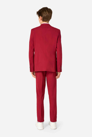 Teenager in einem eleganten burgunderroten Anzug mit weißem Hemd und selbstbewusstem Auftritt. Perfektes formelles Outfit für besondere Anlässe, Hochzeiten und Partys. Ansicht von hinten.