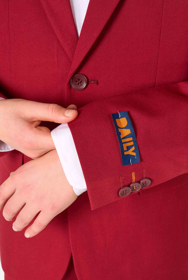 Teenager in einem eleganten burgunderroten Anzug mit weißem Hemd und selbstbewusstem Auftritt. Perfektes formelles Outfit für besondere Anlässe, Hochzeiten und Partys. Ärmel-Nahaufnahme.