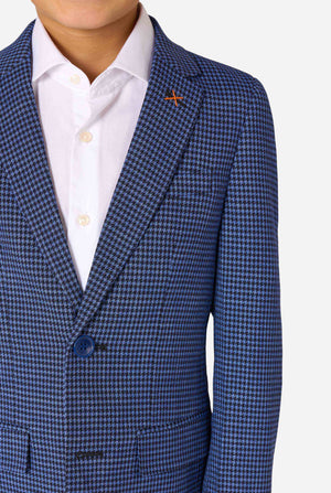 Ein Junge trägt einen dunkelblau-blau karierten Anzug und ein weißes Hemd. Der Anzug hat eine moderne Passform mit zwei Knöpfen und Pattentaschen. Er steht vor einem schlichten weißen Hintergrund. Nahaufnahme der Brust