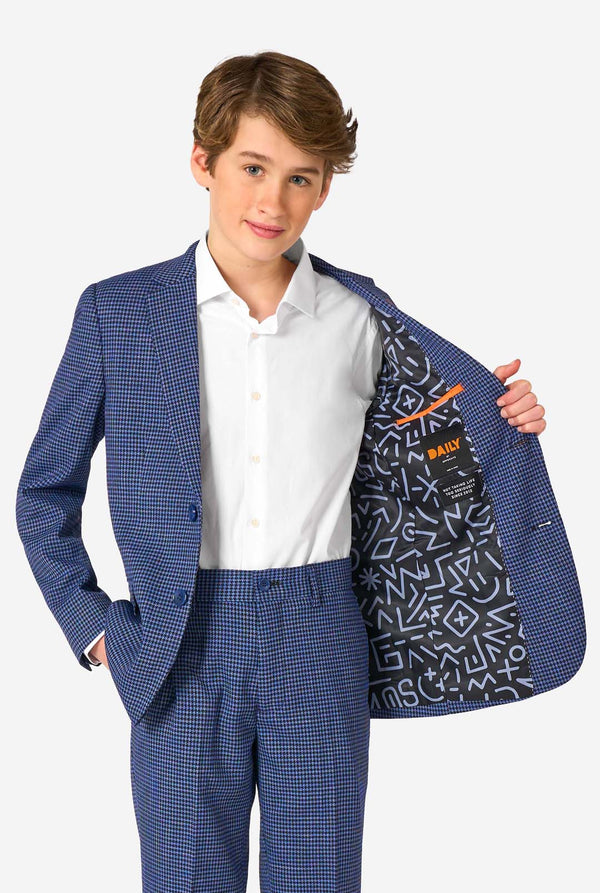 Ein Teenager, der einen dunkelblau-blau karierten Anzug mit einem weißen Hemd trägt. Der Anzug hat eine moderne Passform mit zwei Knöpfen und Pattentaschen. Er steht vor einem schlichten weißen Hintergrund. Hält seine Jacke offen