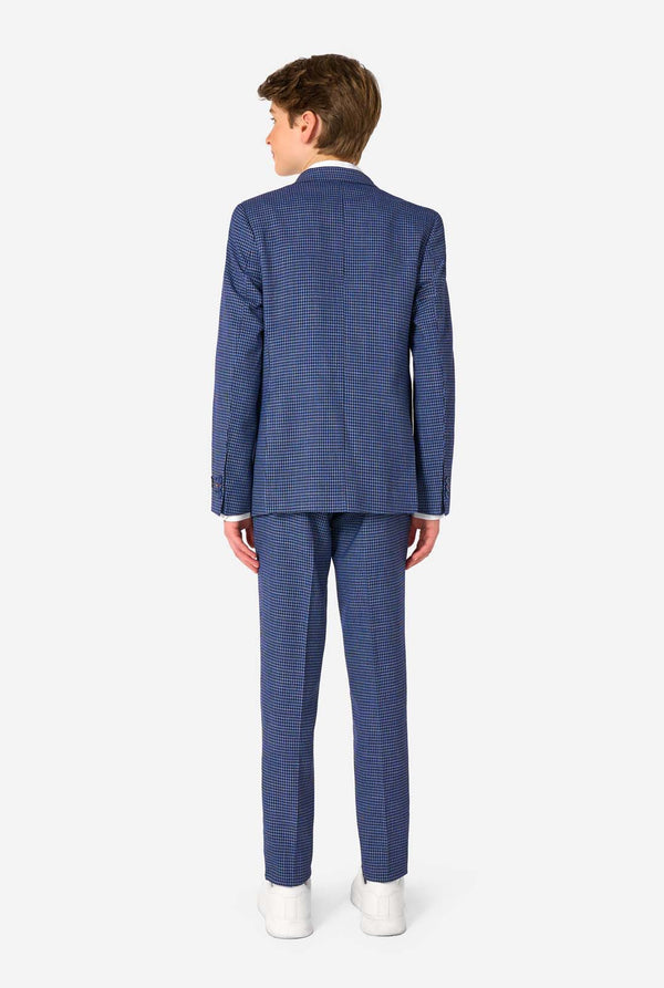 Ein Teenager, der einen dunkelblau-blau karierten Anzug mit einem weißen Hemd trägt. Der Anzug hat eine moderne Passform mit zwei Knöpfen und Pattentaschen. Er steht vor einem schlichten weißen Hintergrund. Ansicht von hinten