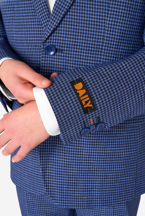 Ein Teenager, der einen dunkelblau-blau karierten Anzug mit einem weißen Hemd trägt. Der Anzug hat eine moderne Passform mit zwei Knöpfen und Pattentaschen. Er steht vor einem schlichten weißen Hintergrund. Nahaufnahme der Ärmel