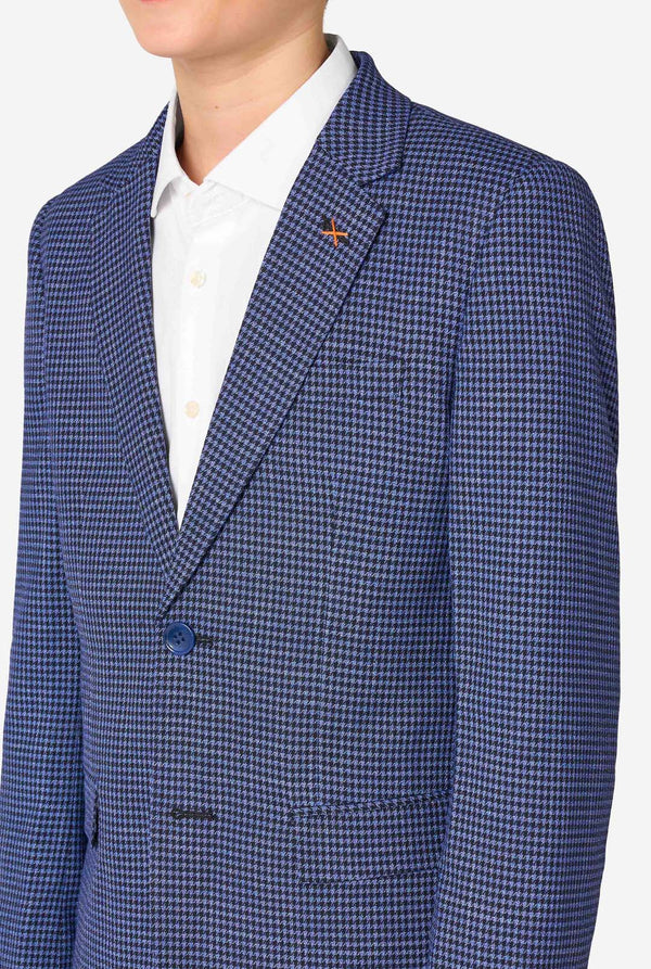 Ein Teenager, der einen dunkelblau-blau karierten Anzug mit einem weißen Hemd trägt. Der Anzug hat eine moderne Passform mit zwei Knöpfen und Pattentaschen. Er steht vor einem schlichten weißen Hintergrund. Nahaufnahme der Brust