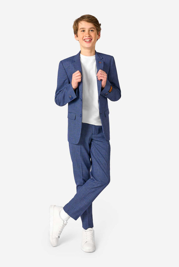 Ein Teenager, der einen dunkelblau-blau karierten Anzug mit einem weißen Hemd trägt. Der Anzug hat eine moderne Passform mit zwei Knöpfen und Pattentaschen. Er steht vor einem schlichten weißen Hintergrund. Ganzkörperbild