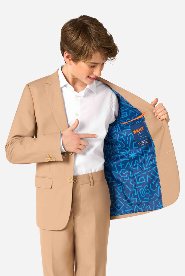 Teenager in einem stylischen hellbraun-beigen Anzug mit weißem Hemd blickt selbstbewusst in die Kamera. Perfektes formelles Outfit für besondere Anlässe, Hochzeiten und Partys. Hält eine Seite der Jacke offen.